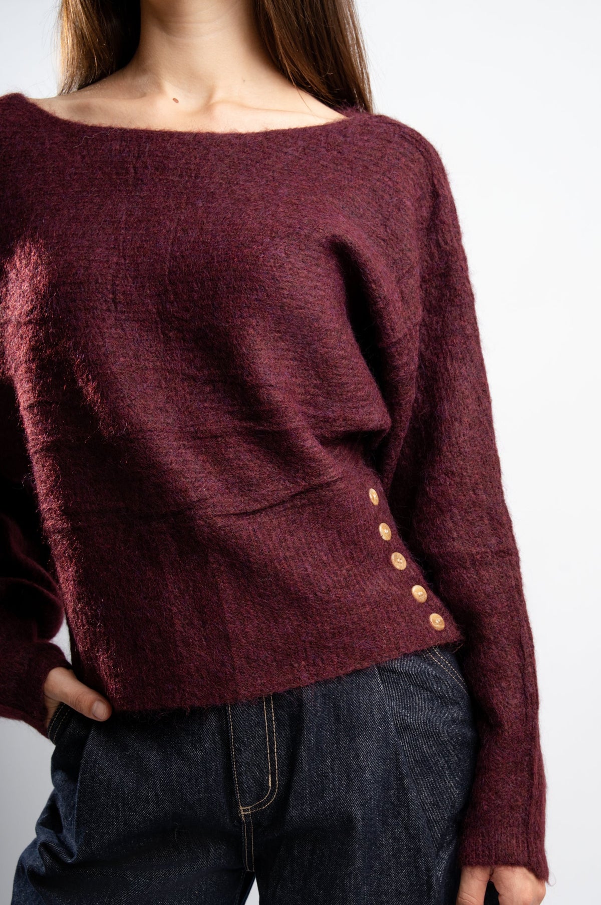 Pull en maille Bordeaux avec boutons latéraux.